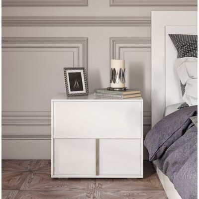 a white nightstand sitting next to a bed on top of a wooden floor