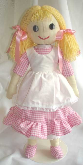 a doll with blonde hair wearing a white dress and pink ribbon around her neck, on a white background