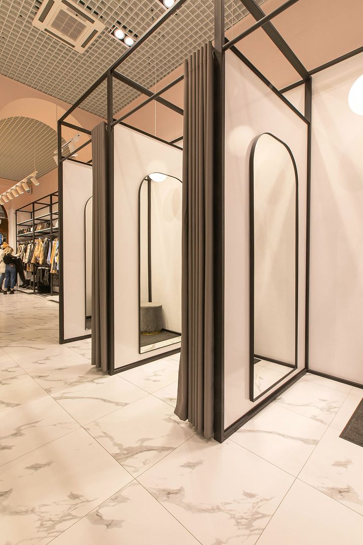 the interior of a clothing store with mirrors on the wall and doors to each side