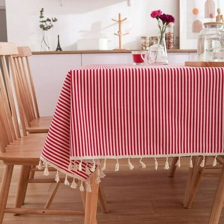 a red and white striped table cloth with tassels sits on a wooden chair