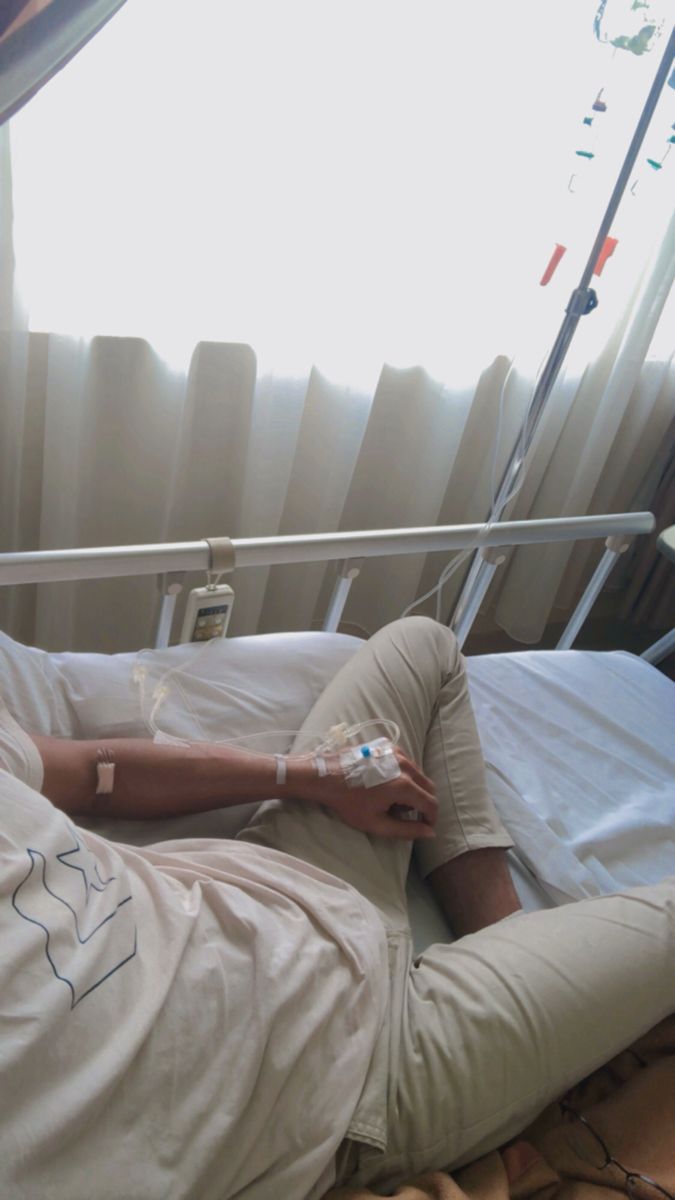 a man laying in a hospital bed with his arm wrapped around an iv and tube