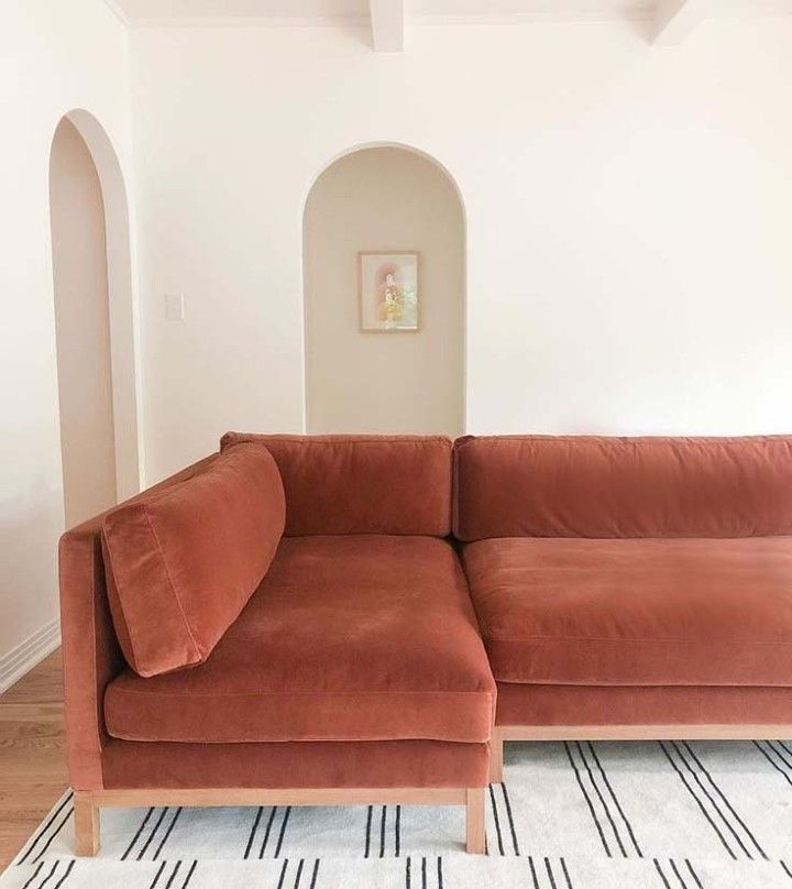 an orange couch sitting on top of a rug in a living room next to a white wall