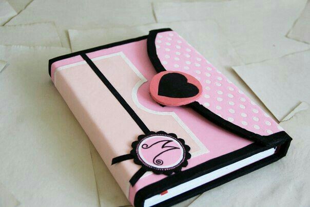 a pink and black book with a heart on the cover is sitting on a white surface