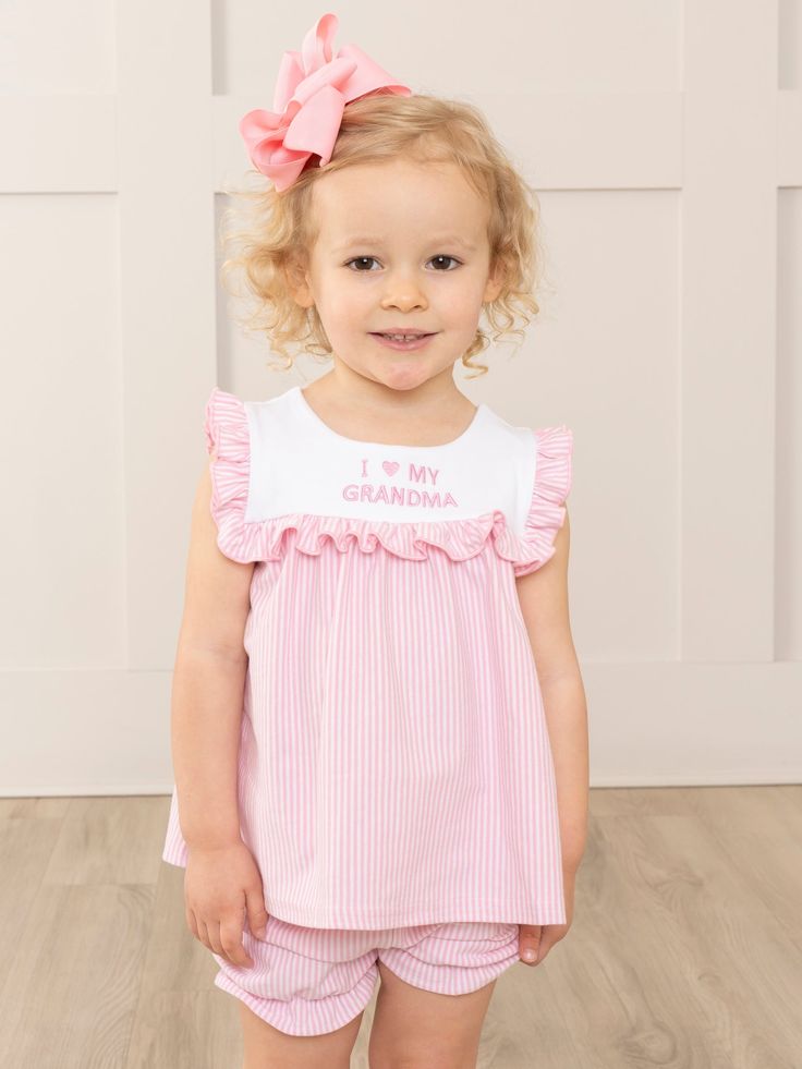 Bask in the sunny warmth of familial bonds with our latest exclusive MNC Basics collection: Family Love. Our soft, comfortable, high quality fabric is back in soft stripes, dainty florals, and ruffles galore. With embroidered messaging expressing love to the family, your little ones will love these spring basics! Show off your little one's love for her grandma in our Pink Grandma Love Ruffle Outfit! This girls' ruffle short set features charming pink and white stripes, accented with an embroidered "I 🩷 My Grandma". The perfect outfit for family gatherings or just hanging out with grandma. So cute, grandma will surely approve!   Fits true to size. Top: 95% Cotton / 5% Spandex Bottom: 95% Cotton / 5% Spandex  Suggested bow color : #1 and #31 Accessories sold separately. Import.  Adalyn is 3 Spring Basics, Grandma Love, Swimwear 2024, Ruffle Outfit, Expressing Love, Baby Gown, Pink And White Stripes, Mom Dress, Ruffle Shorts