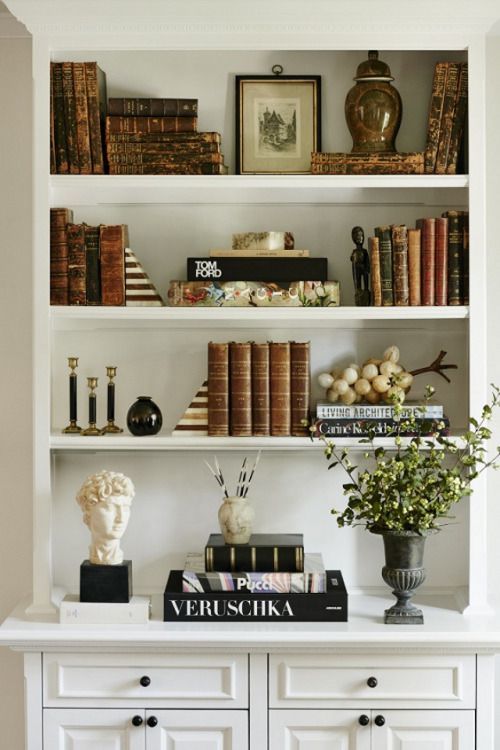 a bookshelf filled with lots of books and vases