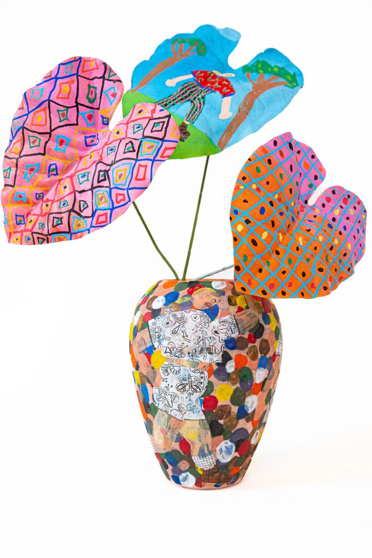 a vase filled with colorful paper flowers on top of a white table