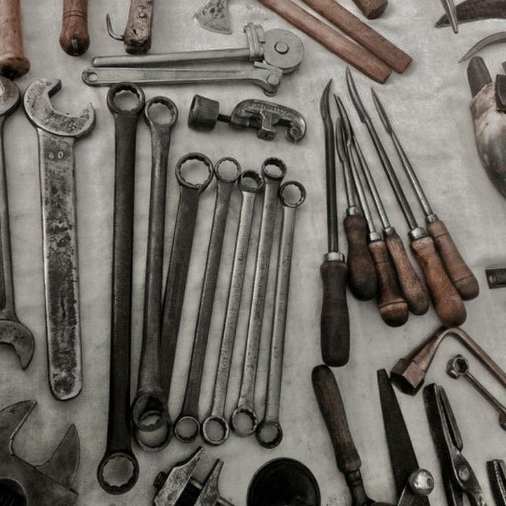 an assortment of tools are displayed on a white tablecloth, including wrenches and hammers