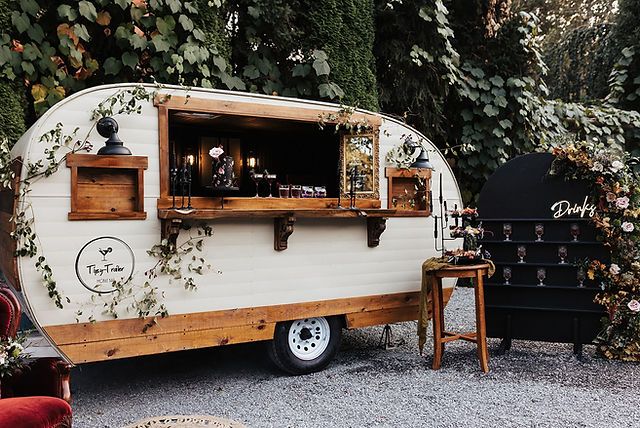 an old trailer converted into a bar with plants growing on the side and shelves above it