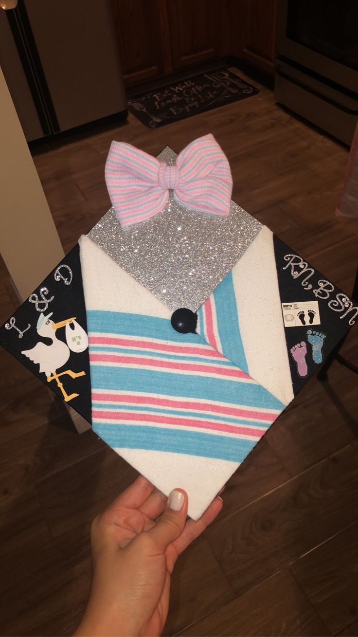 someone is holding up a graduation cap made out of paper and fabric with a bow tie on it