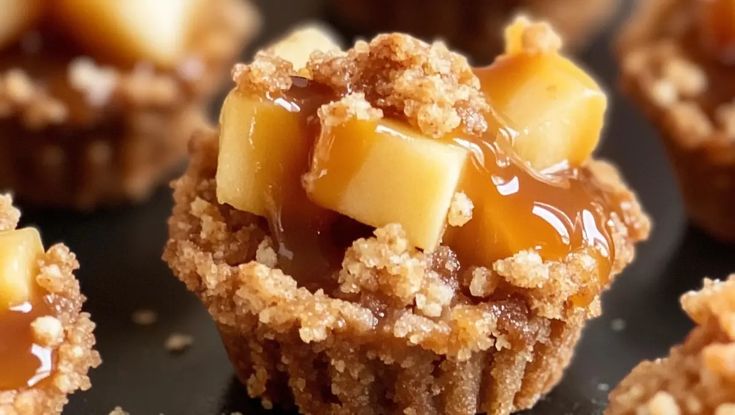 some cupcakes are covered with caramel and crumbs on a black surface