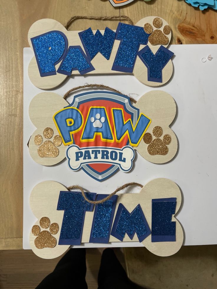 the paw patrol sign is made out of wood and has blue glitter paint on it