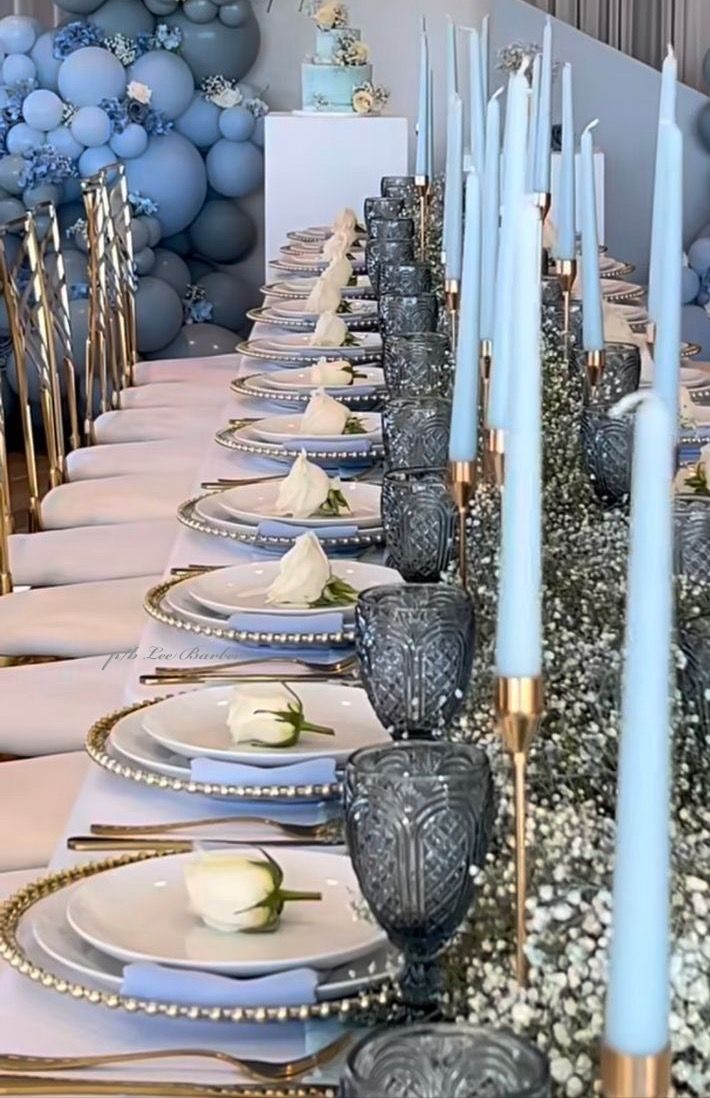 a long table is set with blue candles and white plates for an elegant dinner party