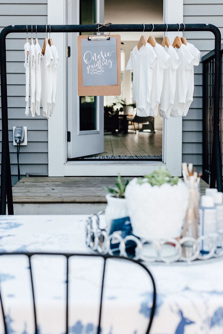 an outdoor table with clothes hanging from it's hooks and the door to a house