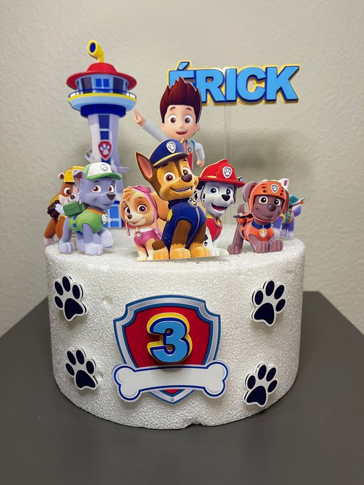 a birthday cake decorated with cartoon characters and paw patrol figures on it's top