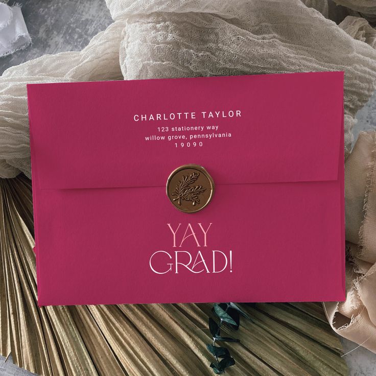 a close up of a pink envelope with a coin on it and the words yay grad written in white