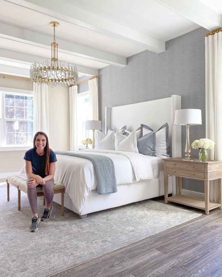 a woman sitting on a bench in front of a bed