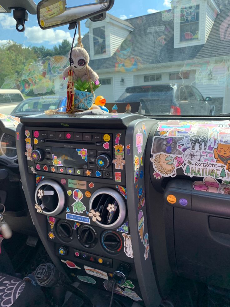 the interior of a car decorated with stickers and decorations, including a teddy bear