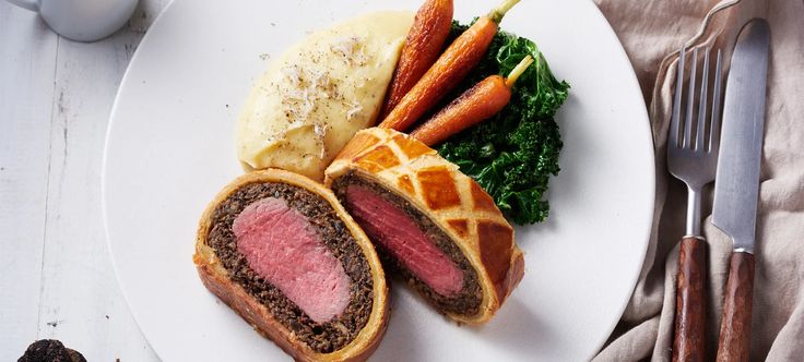 a white plate topped with meat and veggies next to a cup of coffee