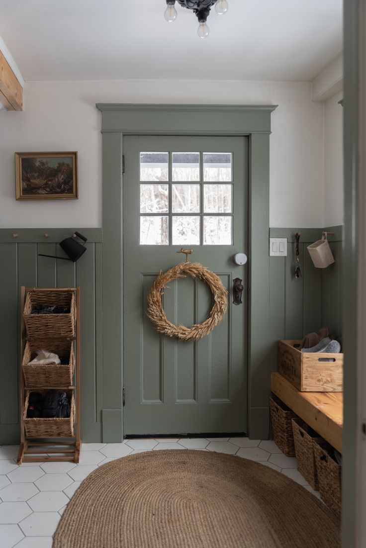 a green front door with a wreath on it and two baskets in the foreground