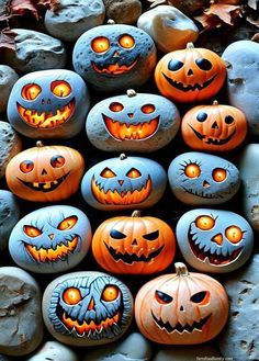 some pumpkins with faces painted on them are sitting in front of rocks and leaves