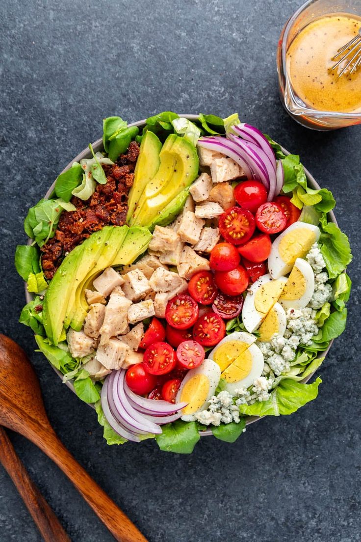 a salad with meat, lettuce, tomatoes, onions and avocado