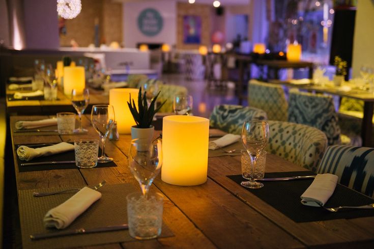 a table with candles and place settings on it in a restaurant or dining room setting