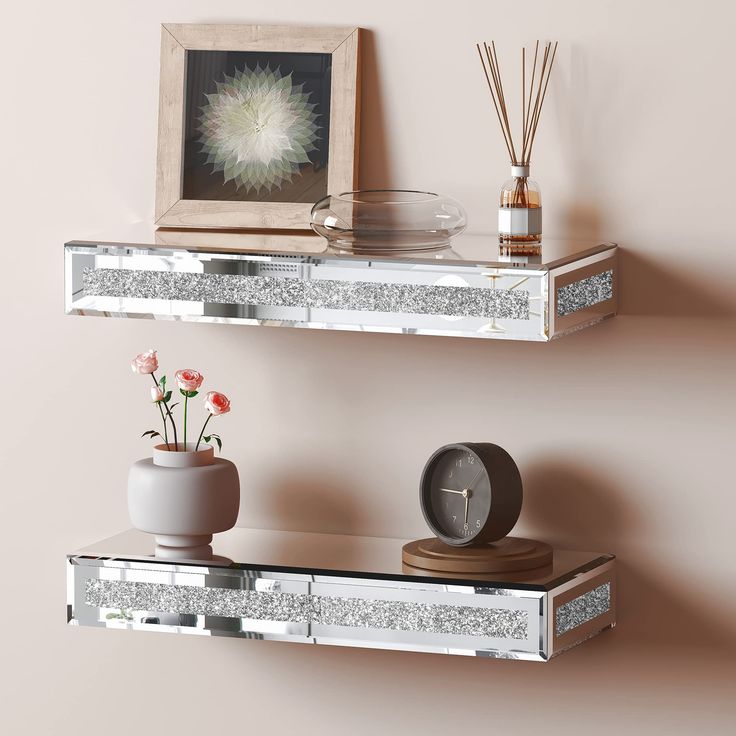 two mirrored shelves with vases and flowers on them next to a framed photograph, candle holder and clock