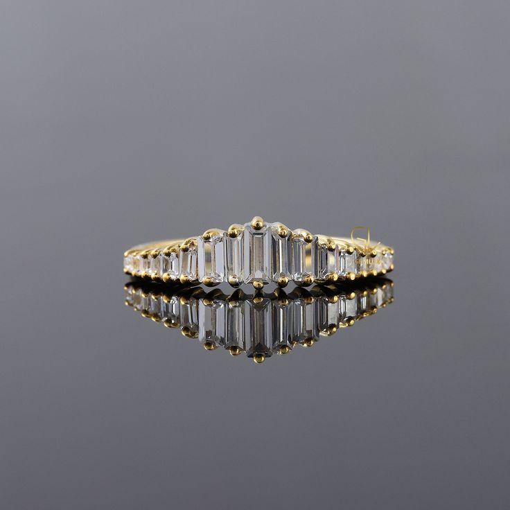 an emerald cut diamond ring on a reflective surface