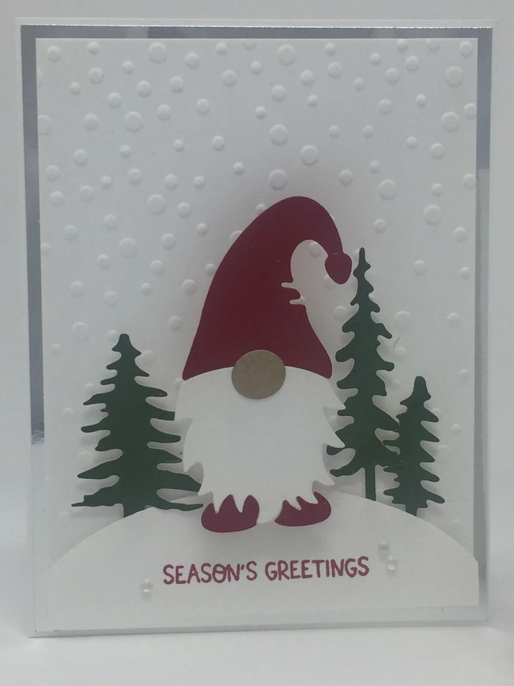 a christmas card with an image of a gnome in the snow, and pine trees