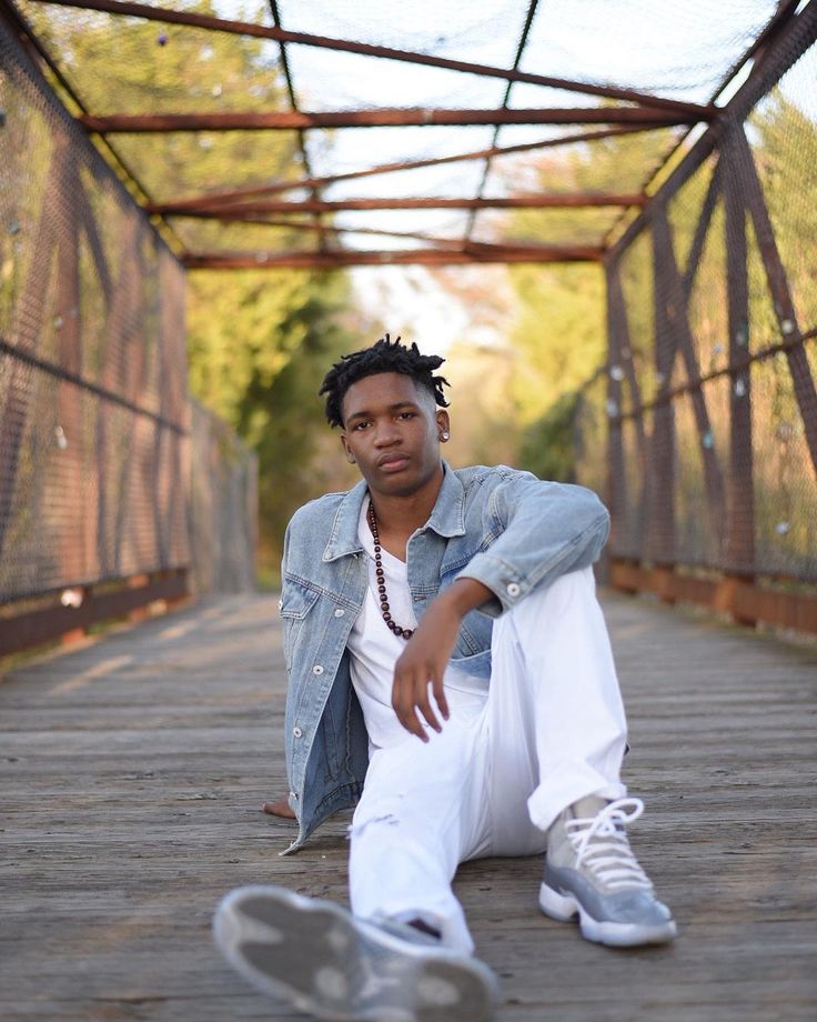 a young man sitting on the ground with his foot propped up in front of him