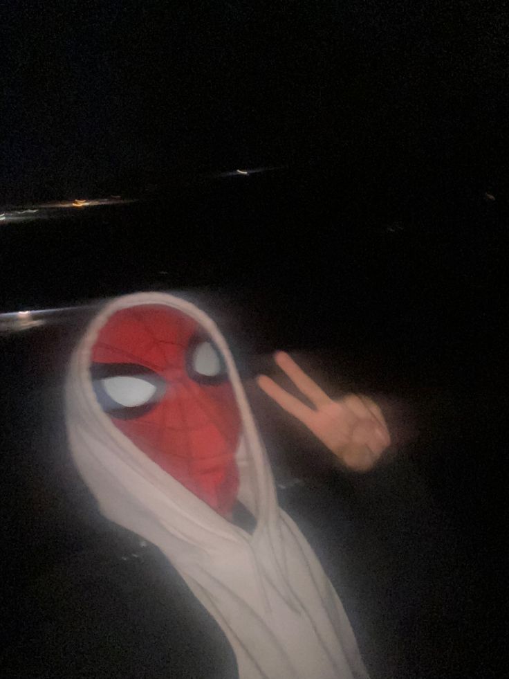 a person wearing a spider man mask with their fingers up