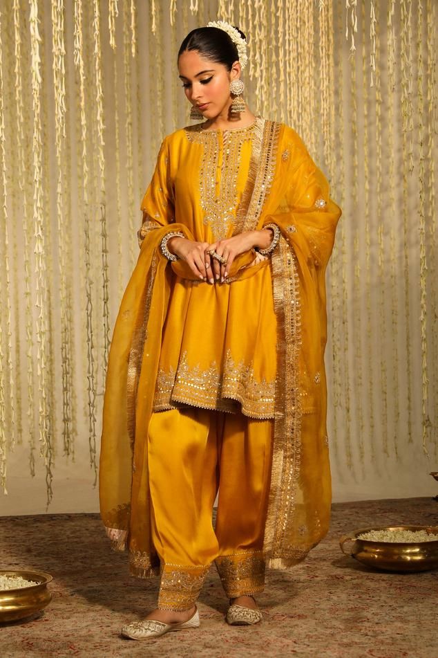 Mustard silk chanderi kalidar with thread embroidered floral patterns embellished by sequins. Comes with matching dogri salwar and kinari lined dupatta.
Components: 3
Pattern: Embroidered
Type Of Work: Thread, Sequin
Neckline: Round
Sleeve Type: Three quarter
Fabric: Kurta: Silk Chanderi, Dogri Salwar: BottomBamberg Satin, Dupatta: Silk Organza
Color: Yellow
Other Details: 
Flared silhouette
Occasion: Sangeet,Mehendi and Haldi - Aza Fashions Mehendi Outfit, Tulip Pants, Haldi Outfits, Jayanti Reddy, Salwar Pattern, Yellow Suit, Short Tunic, Zardozi Embroidery, Women Kurta