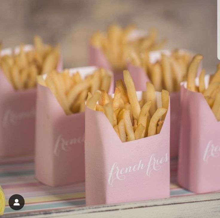 small pink boxes filled with french fries on top of a table