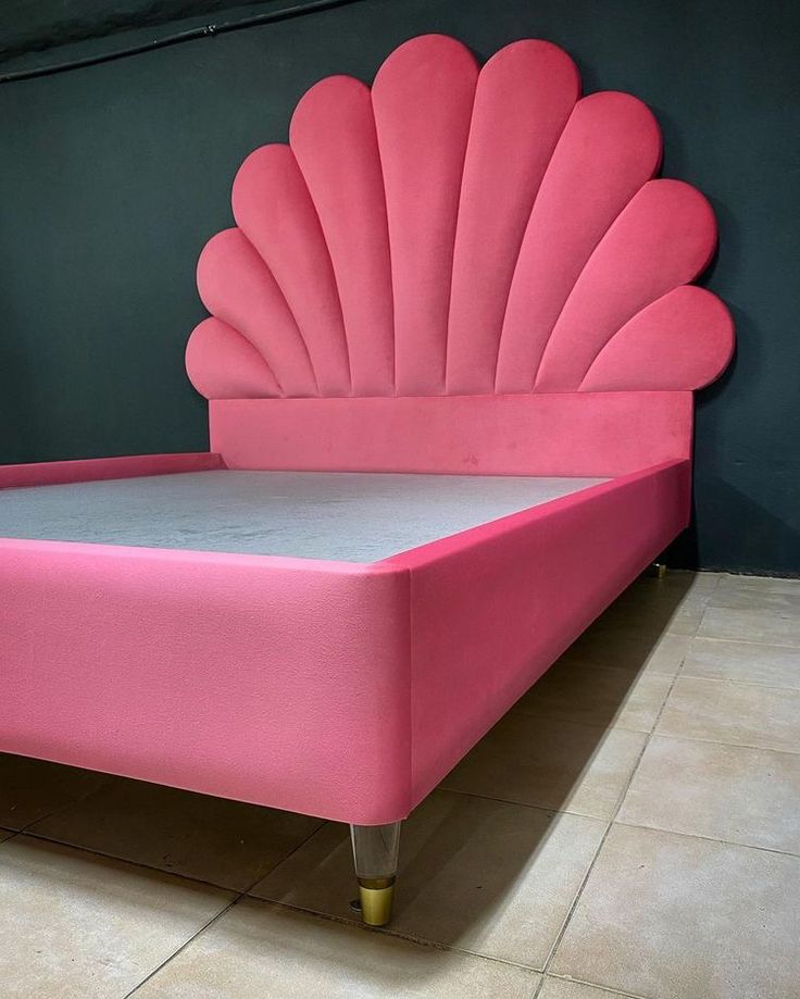 a pink bed with a large shell shaped headboard and foot board on the side