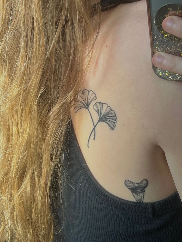 a woman with a tattoo on her shoulder holding a cell phone