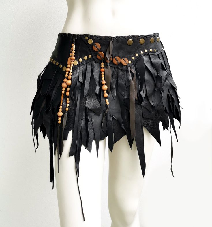 a white mannequin wearing a black leather skirt with wooden beads and tassels