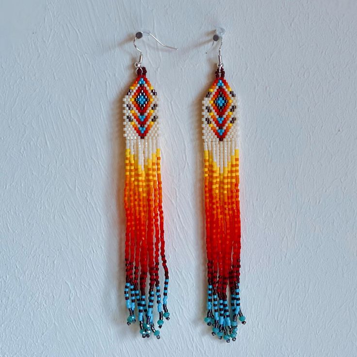 Handmade Huichol Earrings - Intricate Beadwork by Indigenous Artisans from Mexico Handmade by Huichol artisans, an indigenous people of Mexico, these earrings showcase the mastery of fine beadwork that the Huichol are renowned for. This amazing pair features a cascade of powerful colours that has a wonderful effect when wearing them.  ✨ What makes them special? Intricate designs: Each pair is crafted using fine beads and this is what creates these amazing intricate color patterns that reflect Huichol tradition and spirituality. Handmade with care: Every piece is meticulously designed and beaded by hand by Huichol families, making no two pairs exactly alike. Cultural significance: The Huichol people are known for their deep connection to nature, and their art reflects sacred symbols and sto Artisan Hand-strung Earrings For Gift, Traditional Hand-strung Earrings For Gifts, Handmade Southwestern White Earrings, Artisan Hand-strung Round Bead Earrings, Artisan Hand-strung Dangle Earrings, Handmade Southwestern Multicolor Earrings, Artisan Multicolor Hand-strung Beaded Earrings, Multicolor Hand-strung Bohemian Earrings, Multicolor Hand-strung Dangle Earrings