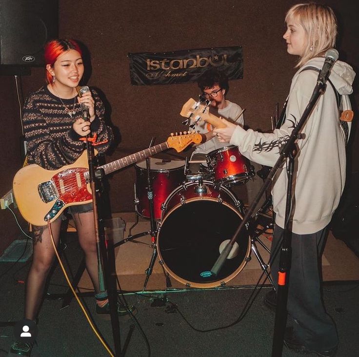 two young women are playing guitars and singing into microphones