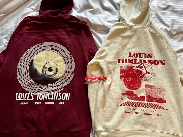 two sweatshirts sitting on top of a bed covered in white and red sheets with the words louis tomkins