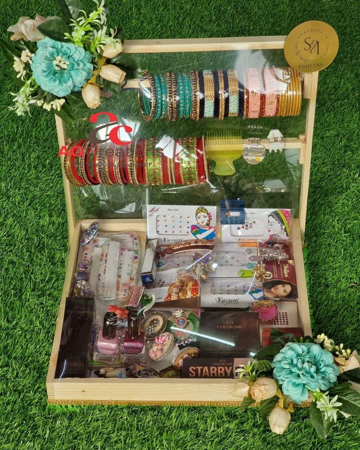 a wooden box filled with lots of different types of bracelets and other items on top of green grass