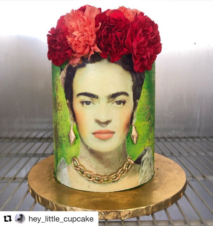 a cake decorated with fridace and flowers on top of a metal rack in a kitchen