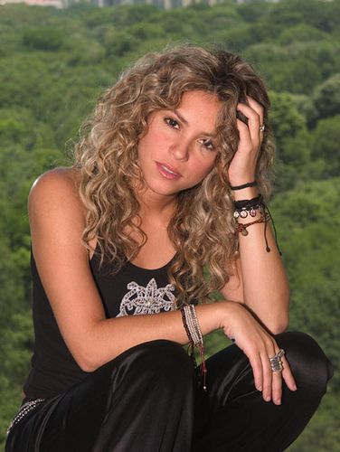 a beautiful young woman sitting on top of a rock