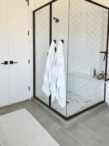 a bathroom with a glass shower door and white towels