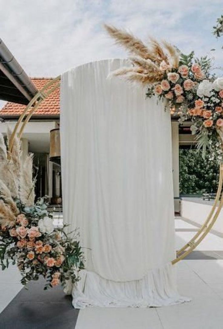 an arch decorated with flowers and pamodia stands in front of a white building