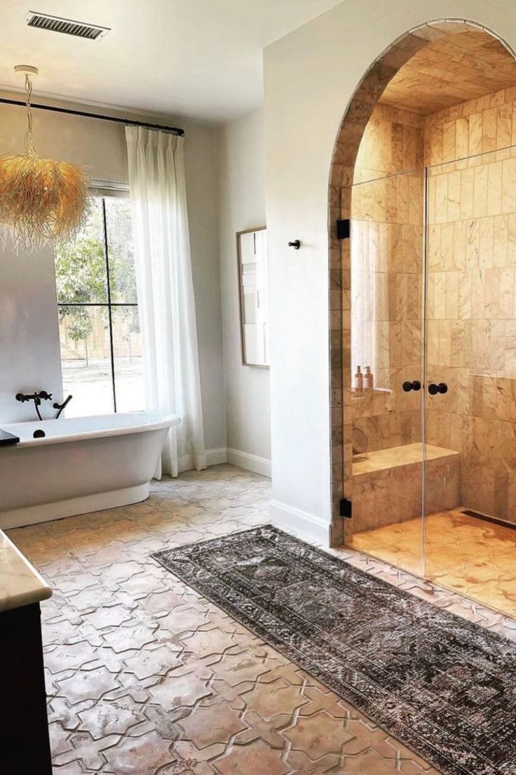 a bath room with a walk in shower next to a tub and a rug on the floor