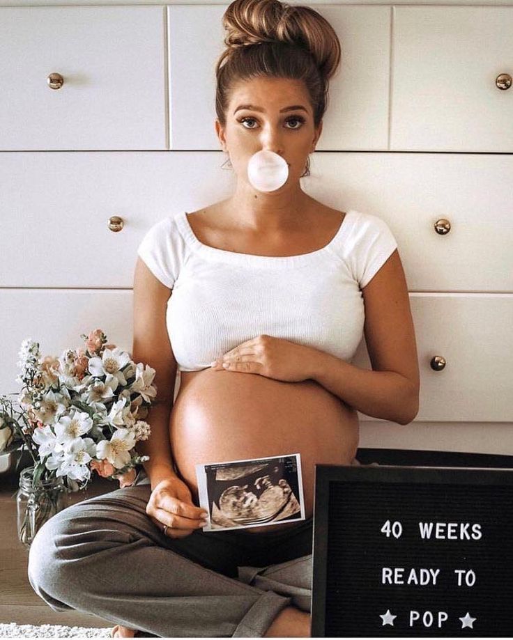 a pregnant woman is sitting on the floor with her pacifier in front of her mouth