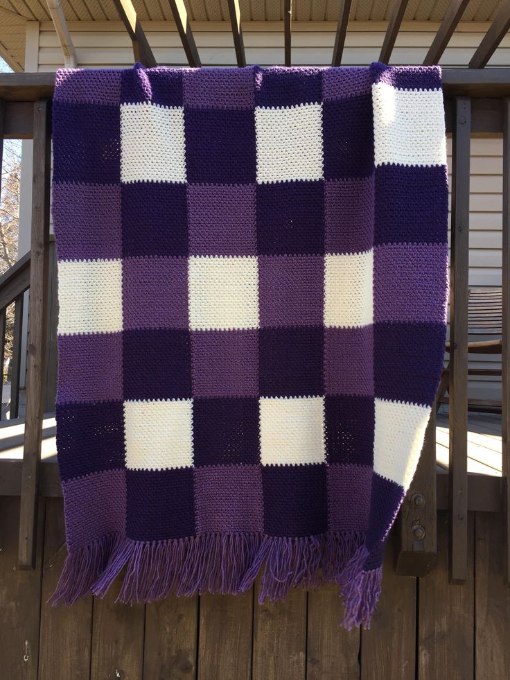 a purple and white checkered blanket hanging on a porch