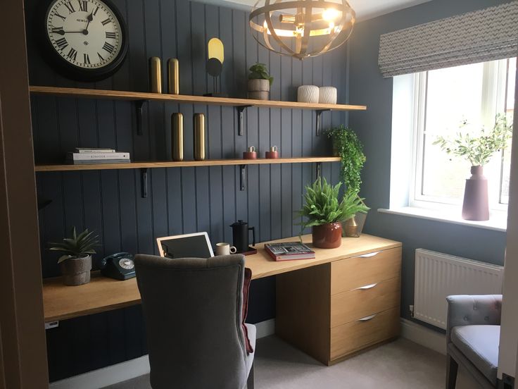 a room with a desk, chair and clock on the wall next to it's windows