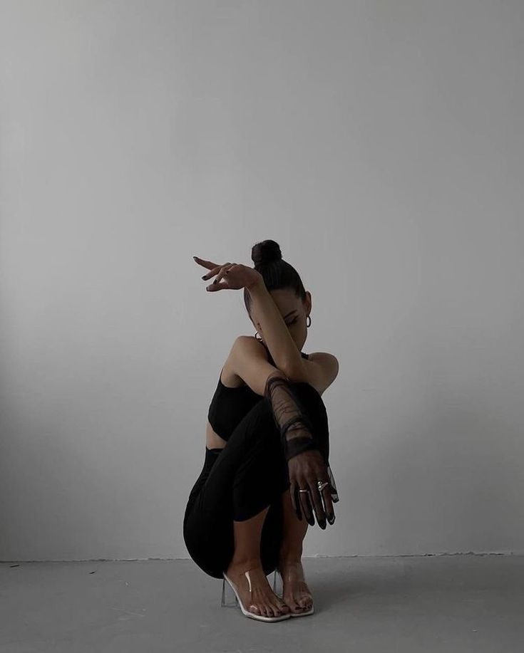 a woman sitting on the ground with her arms stretched out in front of her face