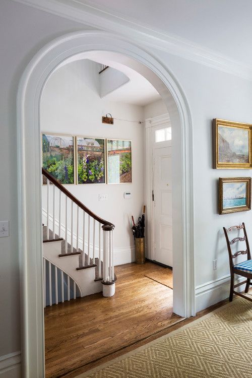 an archway leading to a living room filled with furniture and paintings on the wall above it